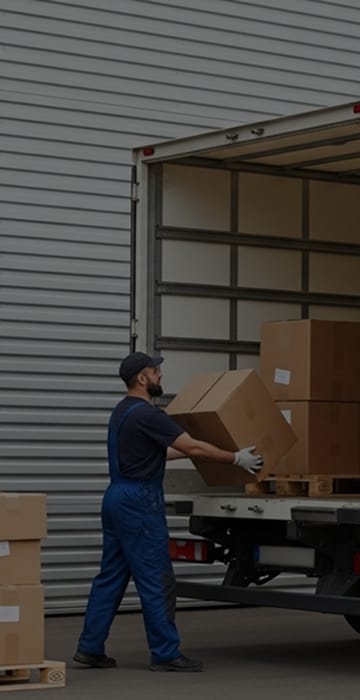 Galpão com caminhão vermelho aberto, pronto para receber carga, representa a agilidade na busca por motoristas autônomos. Agilidade na busca de motoristas